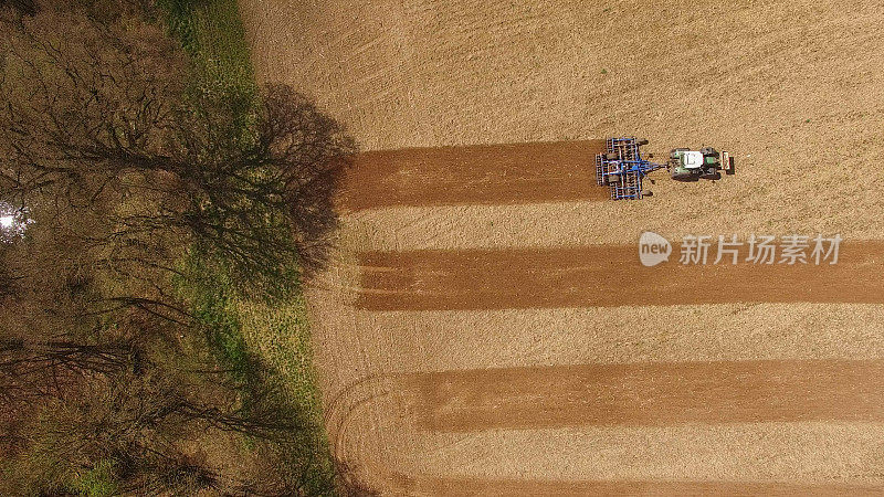 鸟瞰图的拖拉机在一个美丽的农业领域工作在春天的顶部视图