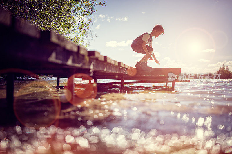 暑假，男孩在湖边的码头上玩耍