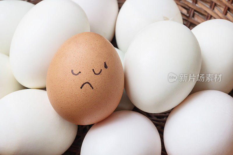 特写棕色鸡蛋与油漆在尝试的脸情绪上堆在白色鸭蛋在木篮子背景