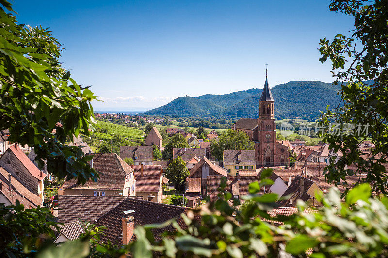 典型的法国村庄，有屋顶，教堂和小山的背景