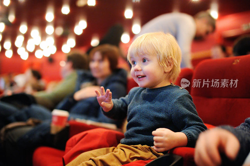 可爱的蹒跚学步的小男孩在电影院看卡通电影