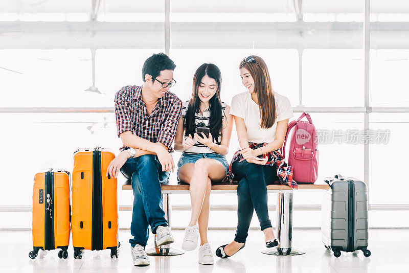 一群年轻的亚洲旅行者使用智能手机和行李一起在机场办理登机手续。出国旅游，暑假旅行，或手机应用技术概念