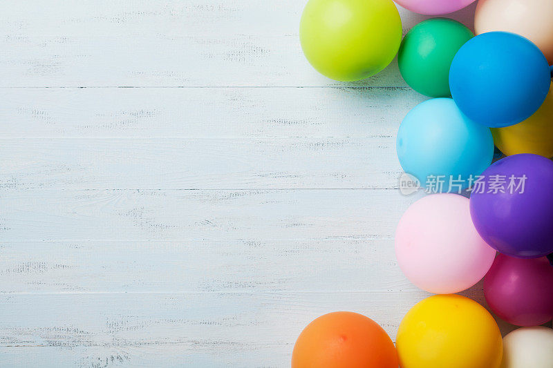 节日的贺卡。堆彩色气球在蓝色木制桌子上的视图。生日或派对背景。平的风格。