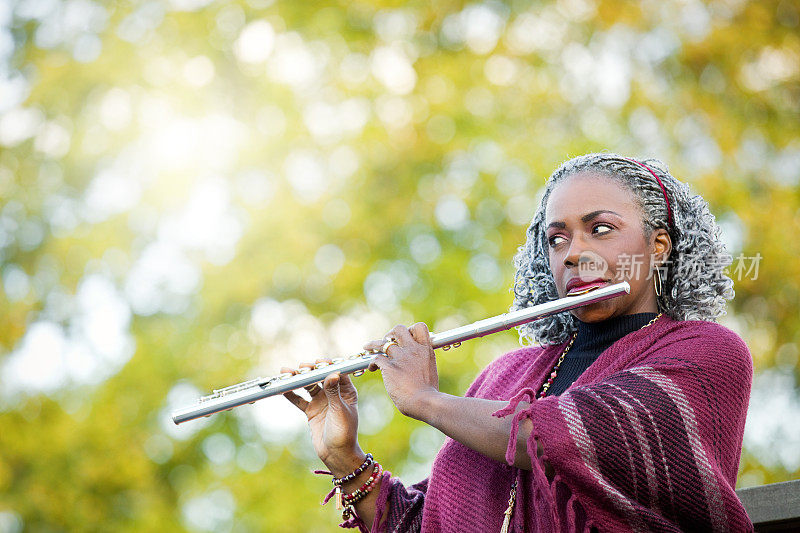 一个女人在户外吹长笛在秋天