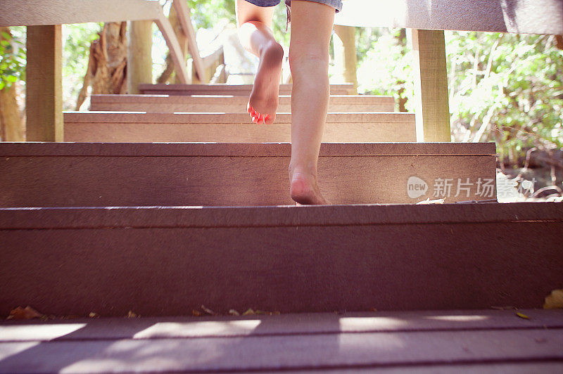 女孩跑上木制台阶的户外脏光脚