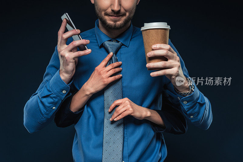 女手用电话和咖啡固定商人的领带孤立在蓝色