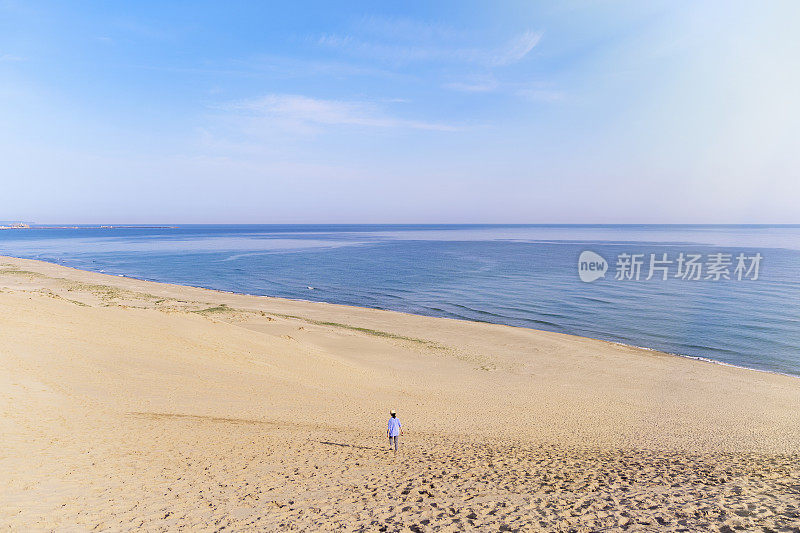 女游客走在沙丘上望着大海