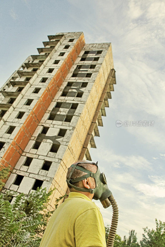 防毒面具的人在破坏的建筑和蓝天背景。