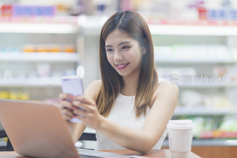 年轻女人坐在便利商店使用手机