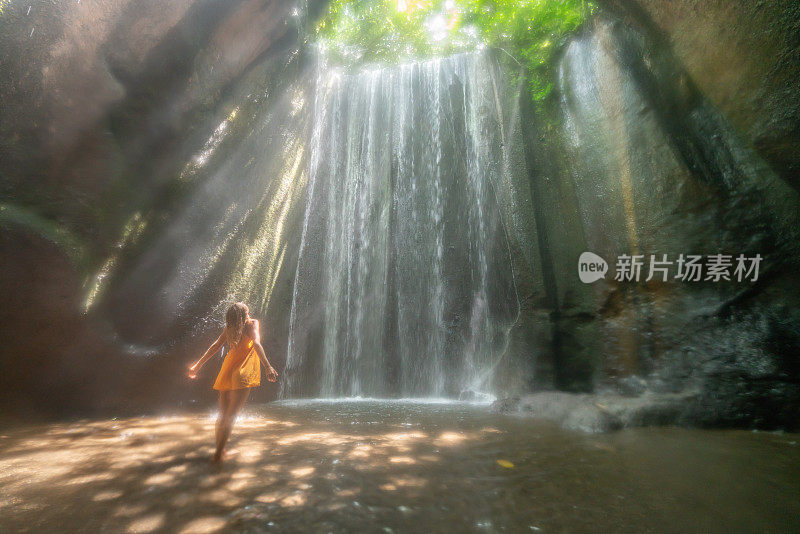 在巴厘岛的热带雨林中，旅行的年轻女子张开双臂拥抱大自然的美丽。人们以自然为旅游理念。