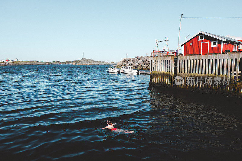 一名妇女在挪威渔场附近冰冷的海水中游泳