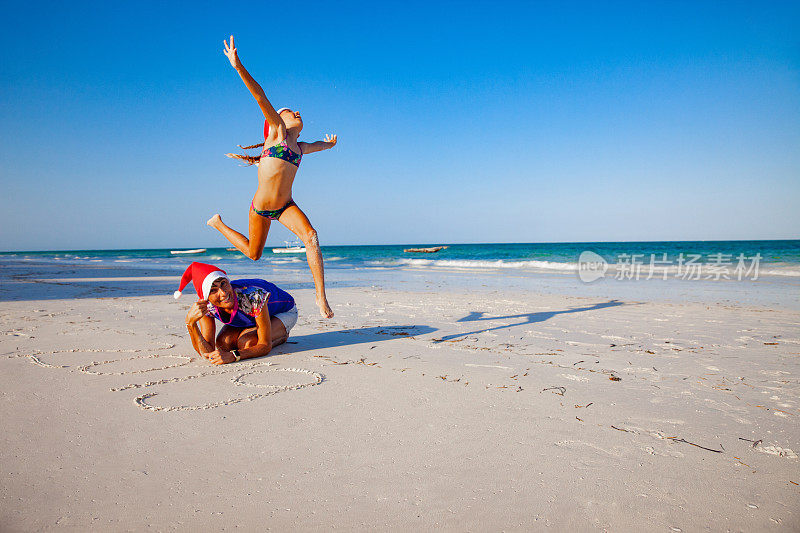 圣诞节的时候，兴奋的小女孩和妈妈一起在海滩上蹦蹦跳跳