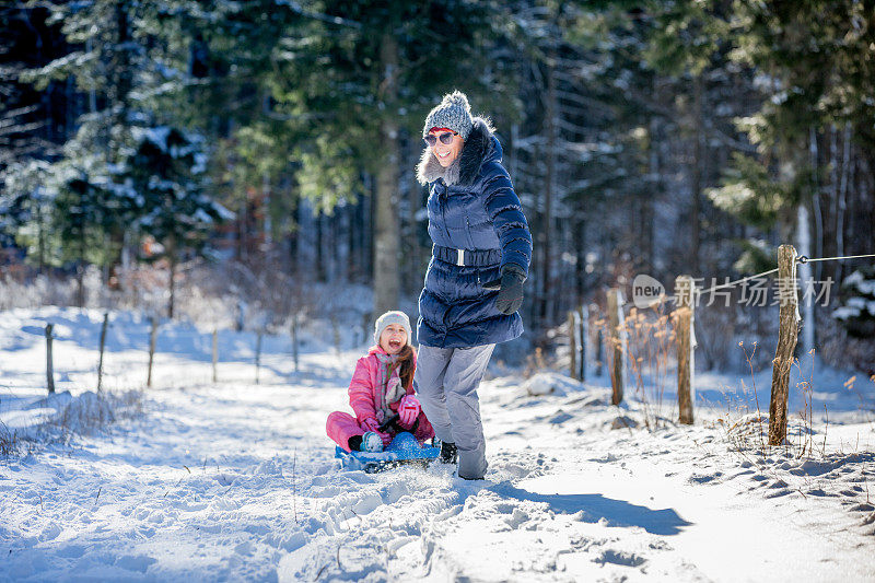 母亲和女儿一起在大自然中享受雪橇