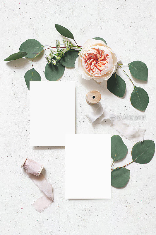 女性婚礼，生日模拟场景。空白纸贺卡，丝带，桉树叶和粉红色的英国玫瑰花。具体表的背景。平放，俯视图，垂直。