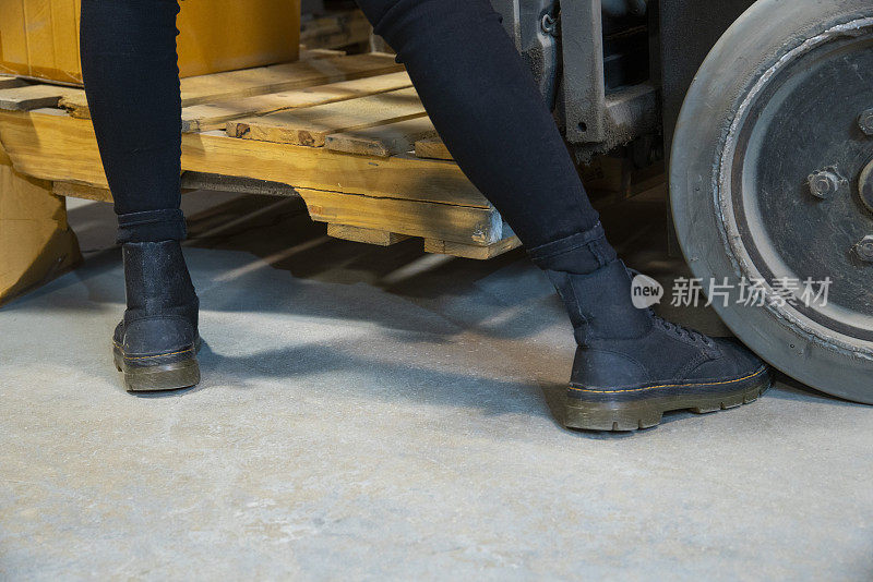 仓库、工业安全的话题。一名女性工人，她的脚在一辆叉车的轮子下。