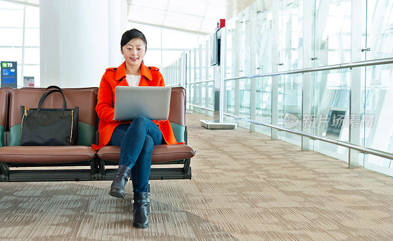 年轻的亚洲女子在机场使用笔记本电脑