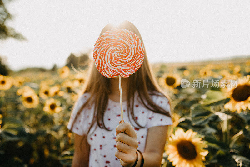 一个年轻女子在向日葵地里拿着糖果