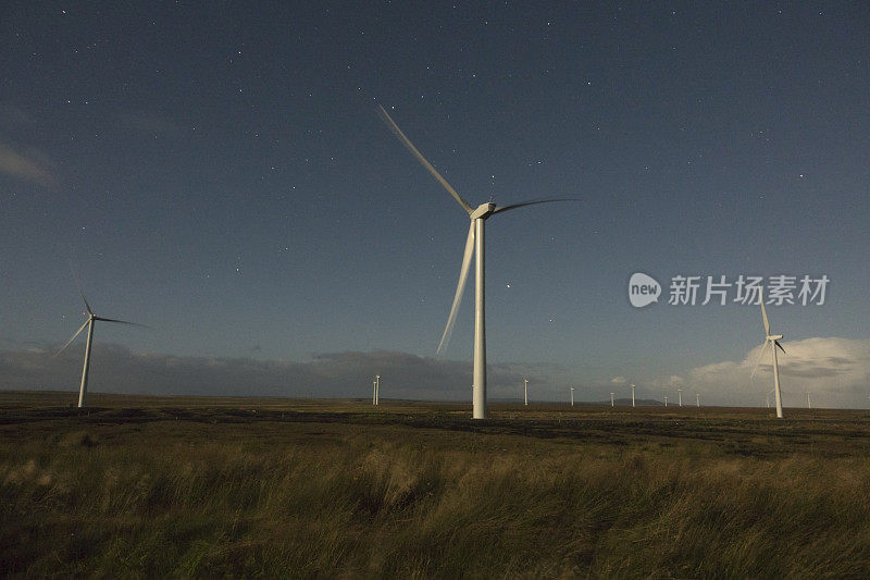 夜间的星星在苏格兰北部荒原阿克基普斯特山的农田上巨大的风力发电机上