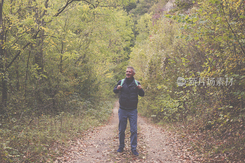 一名成年男子于秋日在美丽的山林中徒步旅行