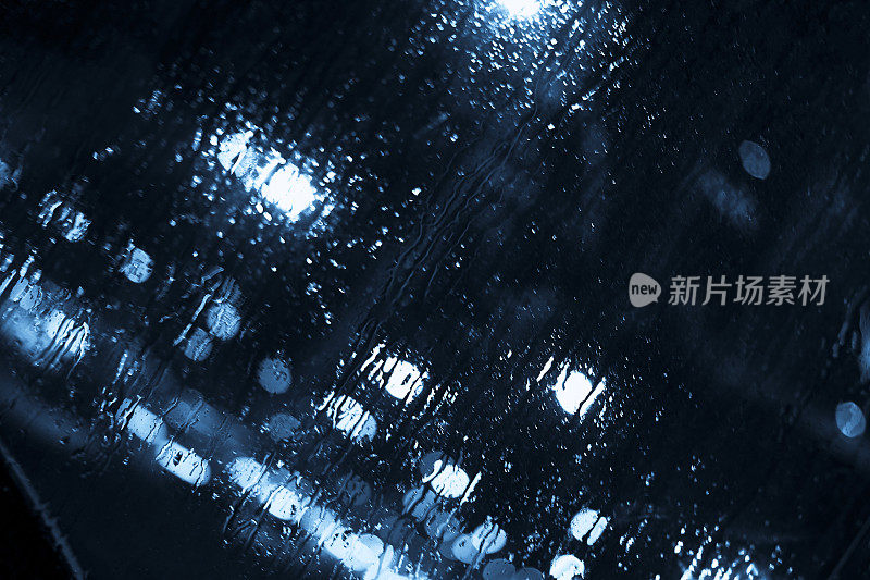 抽象的雨滴落在窗户上，模糊了城市的灯光