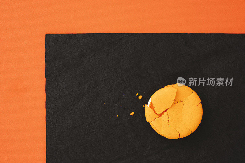 黑色和橙色的背景上有裂痕的橙色杏仁饼干