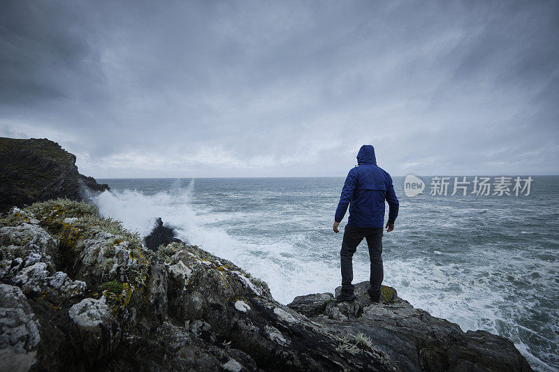 秋天的一个阴天，一个人孤零零地站在悬崖顶上望着大海。