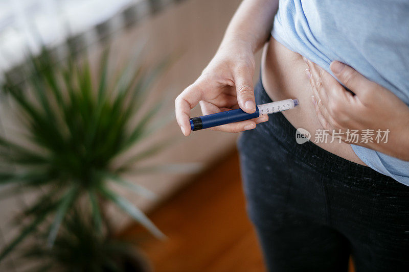 一个女人在胃里注射胰岛素。库存图片