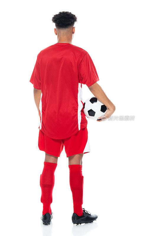 非裔美国青年男子足球运动员，穿着足球制服站在白人背景前，手持足球进行足球运动和使用运动球