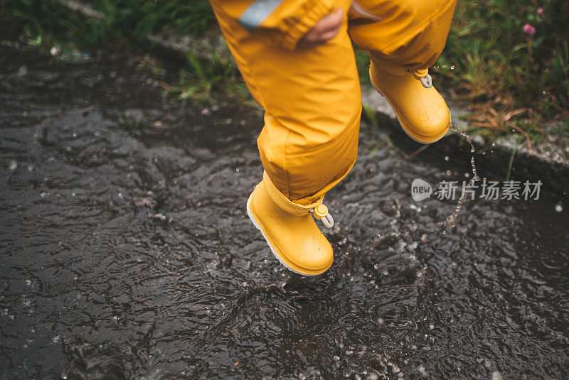 小男孩在雨中玩耍，跳进水里画画