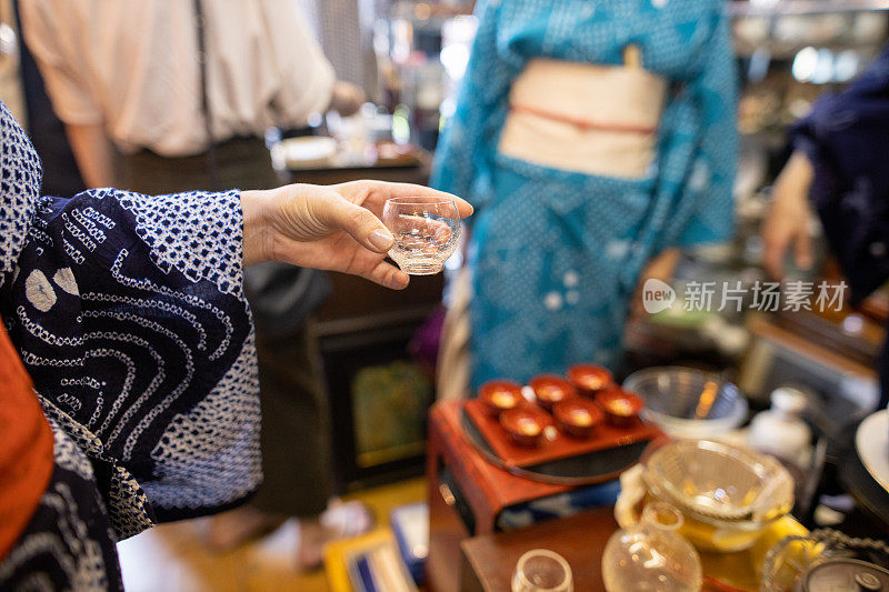 yukata的女人在古董店拿着一杯日本酒