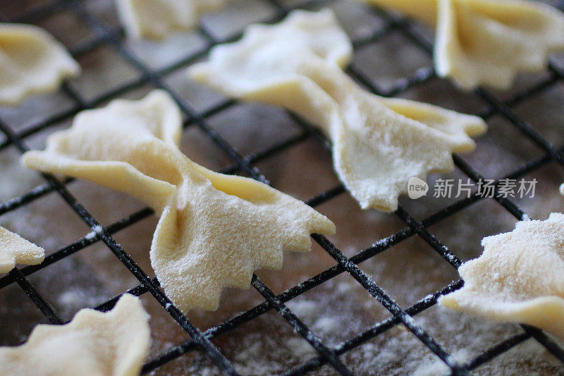 这是自制法法尔面食(蝴蝶结状或蝴蝶状)的特写，撒上面粉，放在金属丝冷却架上晾干，意大利美食