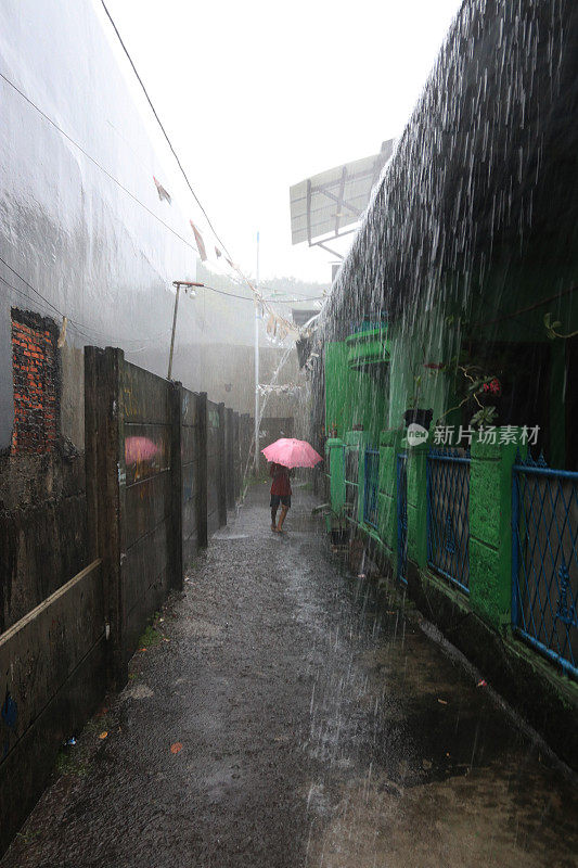 一个小女孩在倾盆大雨中带着雨伞。