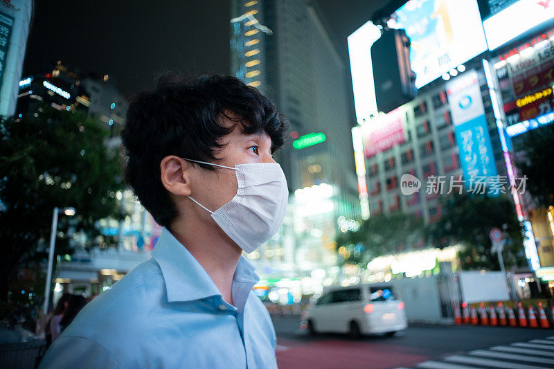 一幅戴着面具的亚洲男子的肖像，展示着城市的夜景