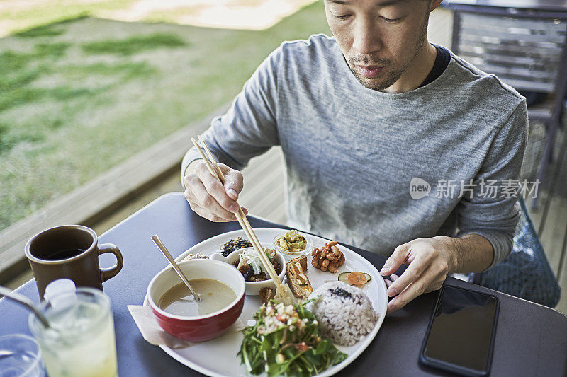 一名日本男子在一家素食咖啡馆的露台上吃素食午餐。