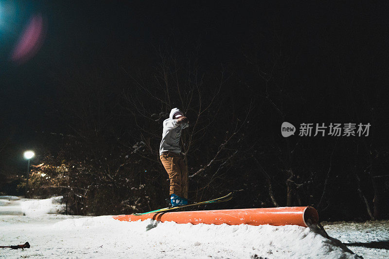 一名自由式滑雪者在晚上碾压滑雪板上的栏杆