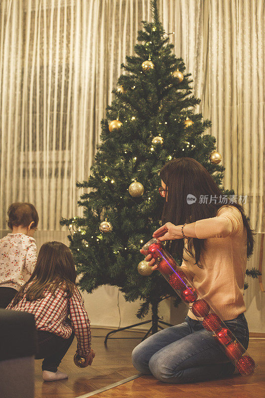 妈妈和她的两个小女儿在装饰圣诞树