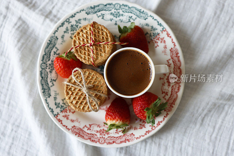 线结燕麦饼干，草莓和一杯土耳其咖啡在红绿图案的盘子，在白色的布餐巾上