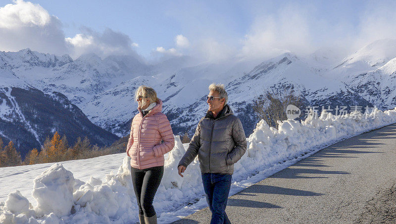 夫妻俩一起走在雪山风景中