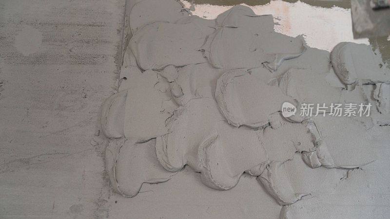建筑工用泥铲把灰泥抹在混凝土墙上以固定金属建筑信标。建筑工用泥铲涂抹灰泥