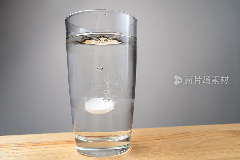 在白色的背景下，将溶解的药片放入一杯水中。
