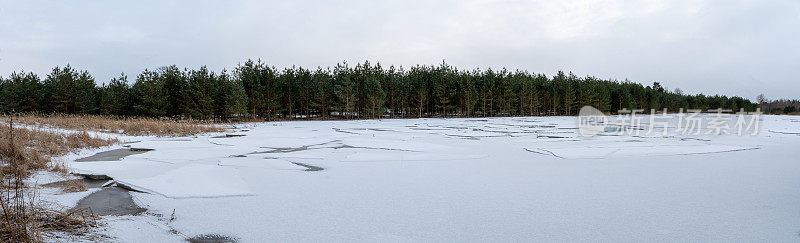 森林湖被冰雪覆盖着。一片水域上的一层层破碎的冰。针叶林中的早春。自然全景