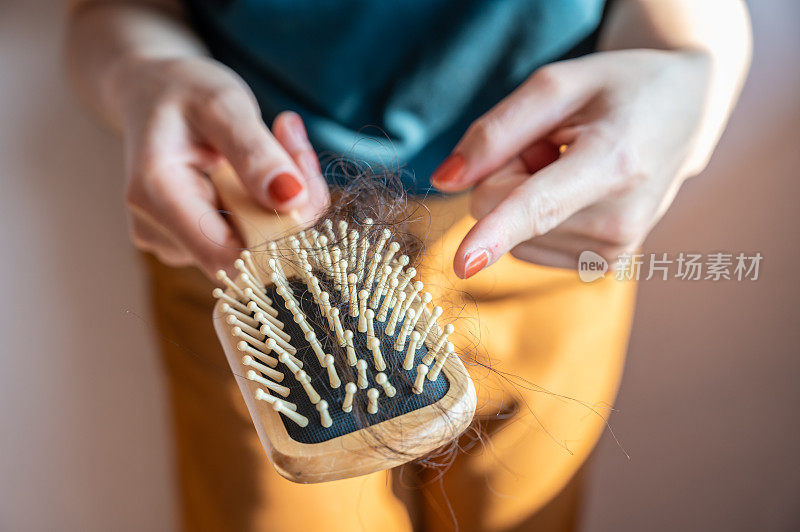 特写的女人拿着梳子凌乱的头发丢失后，梳理她的头发。