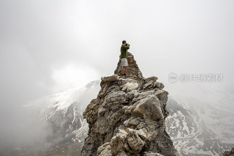 徒步旅行者在岩石顶端放松，用相机拍照