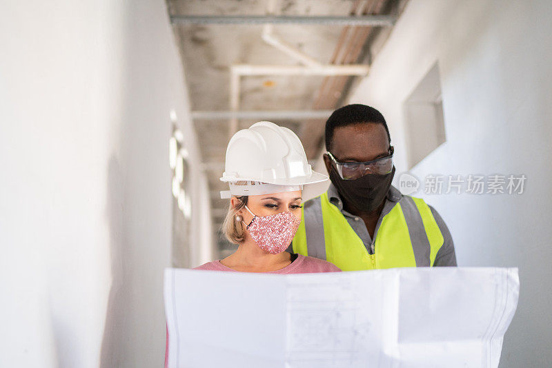 工程师和建筑工人拿着图纸讨论施工——戴着防护口罩