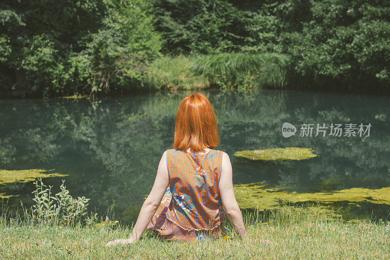 红头发瘦弱的女孩旁边的一个小池塘