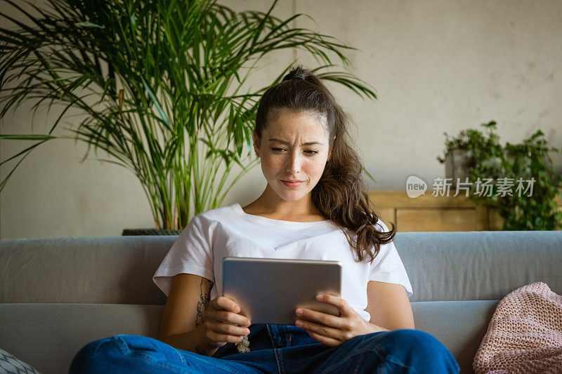 惊讶的年轻女子在家里使用电子平板电脑