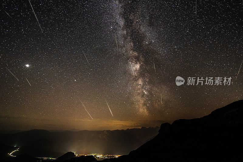 山谷上方的山上，夜空中有许多星星、银河和英仙座