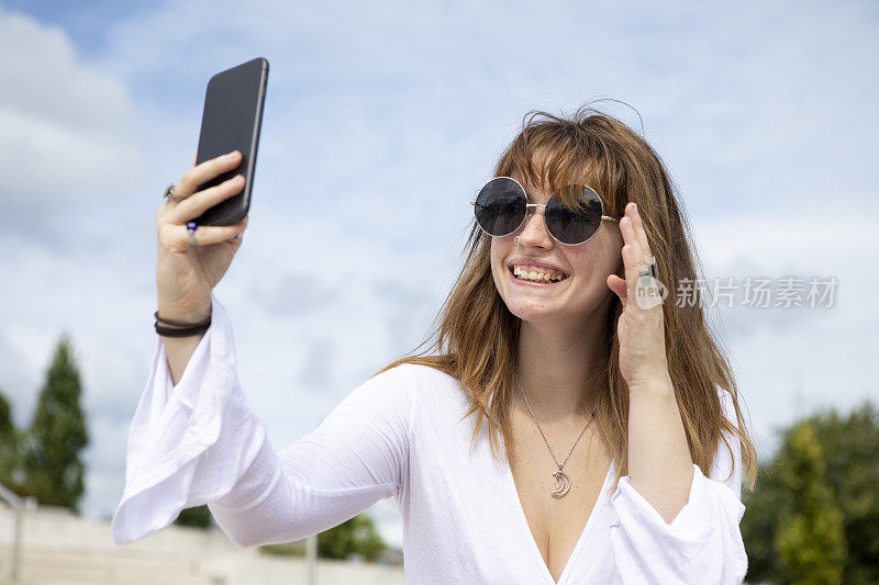 夏天，一名年轻女子坐在石阶上用手机自拍