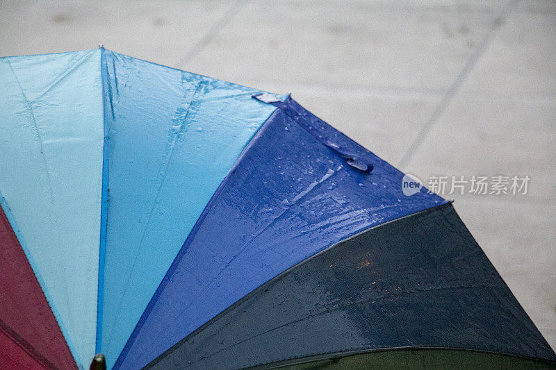 雨点落在彩虹伞上，天以自然为背景