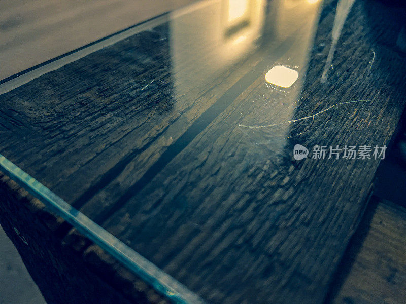 木桌的边缘，上面有玻璃。